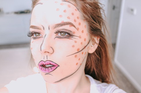 Jodie poses for her easy pop art makeup tutorial for beginners - she has brown hair and fair skin, with bold black lines and red pola dots for the pop art makeup.