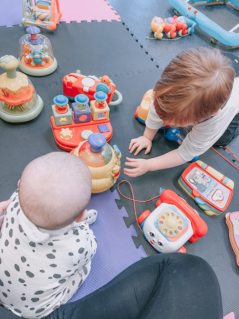 baby and toddler playing with baby toys on padded mats