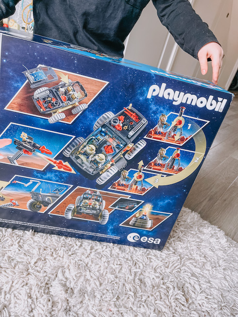 Toddler pointing to back of playmobil box